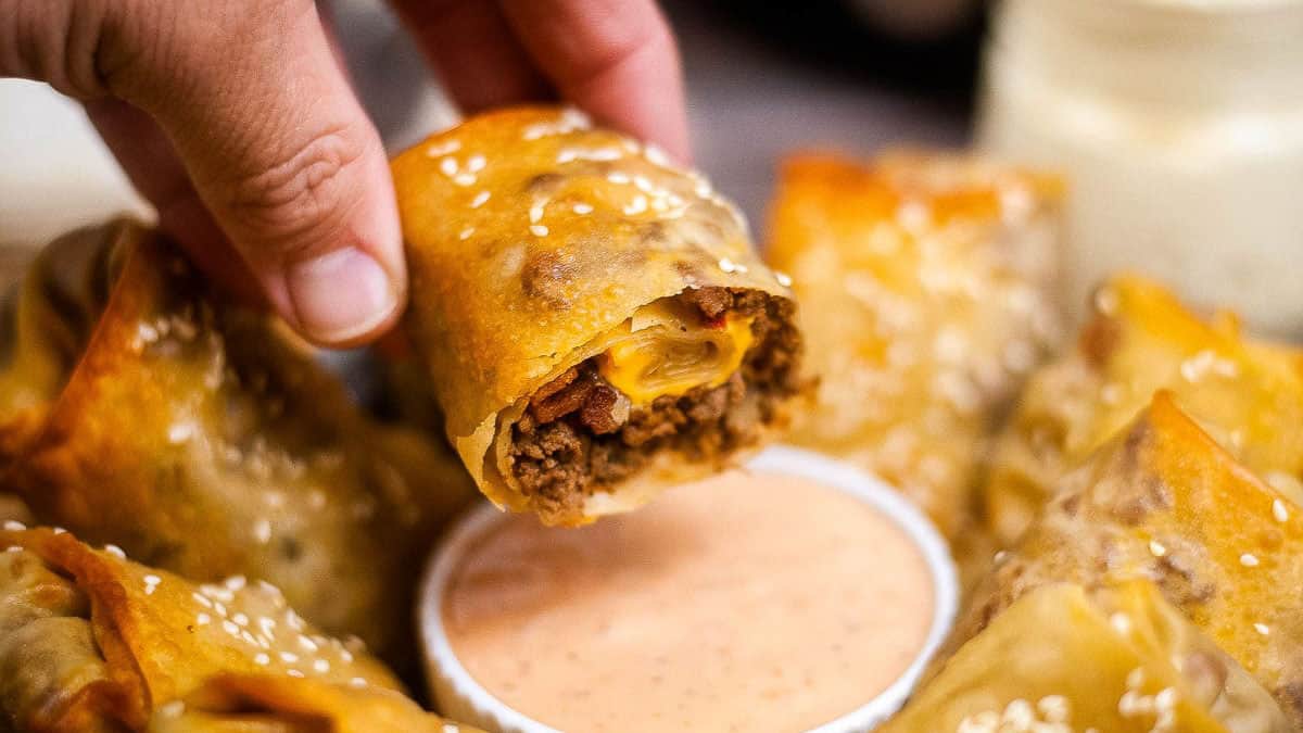 Cheeseburger egg rolls cut in half and dipped into sauce.