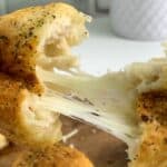 Pulling apart a garlic cheese ball filled with stringy mozzarella cheese.