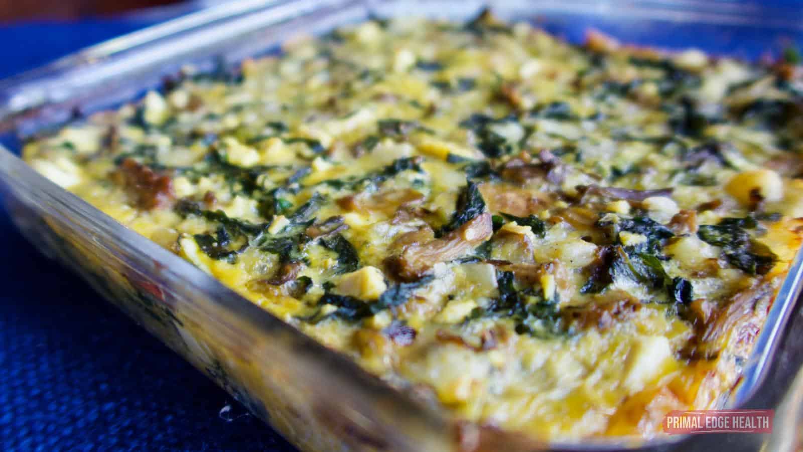 A picture of cheesy casserole in a glass baking dish with blue fabric.