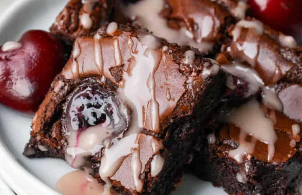 A white plate with chocolate cherry brownies.