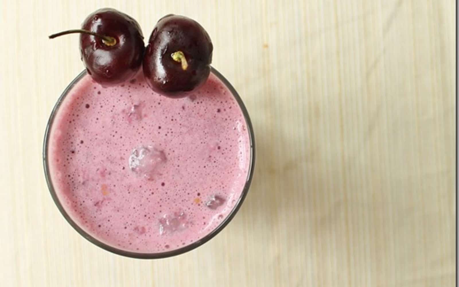 Cherry vanilla almond smoothie garnished with two cherries in a glass.