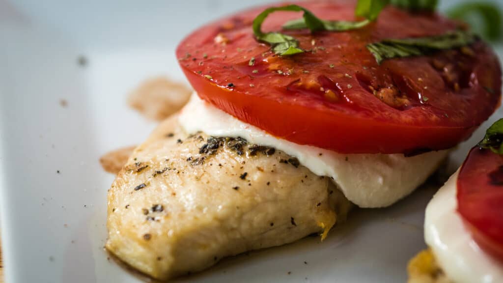 chicken breast topped with melted mozzarella cheese and tomato.