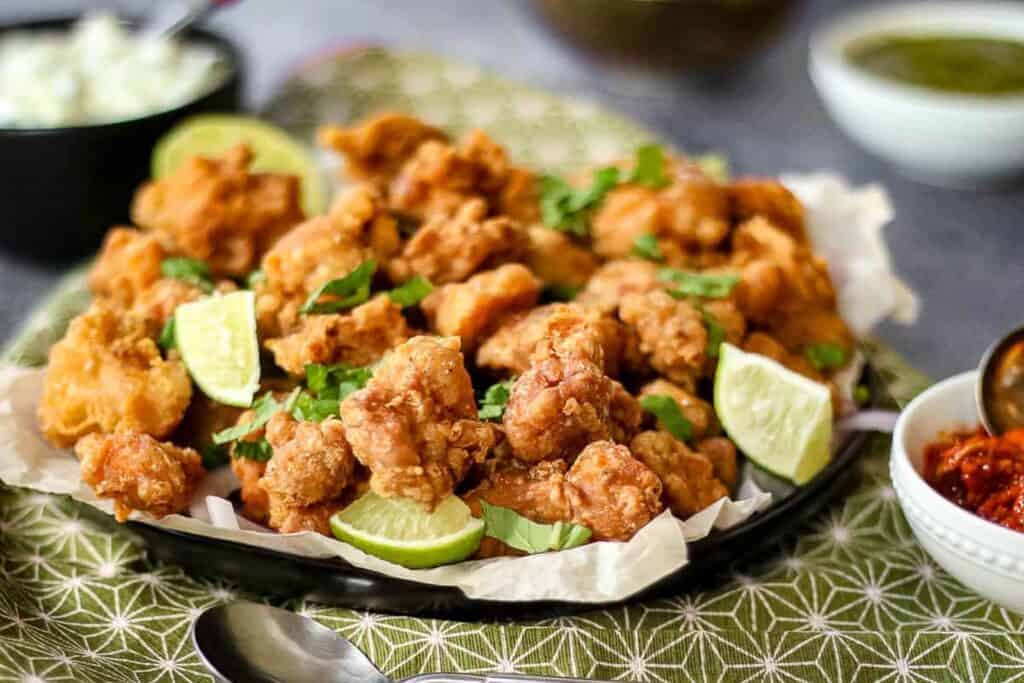 Low angle shot of chicken pakora on a plate with a green napkin.