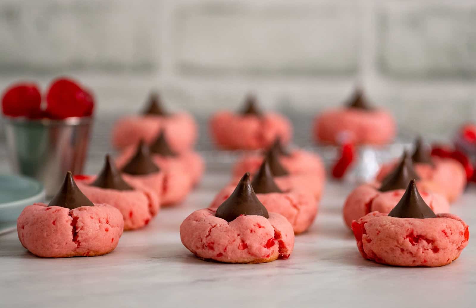 Cherry cookies topped with chocolate kisses on a plate.