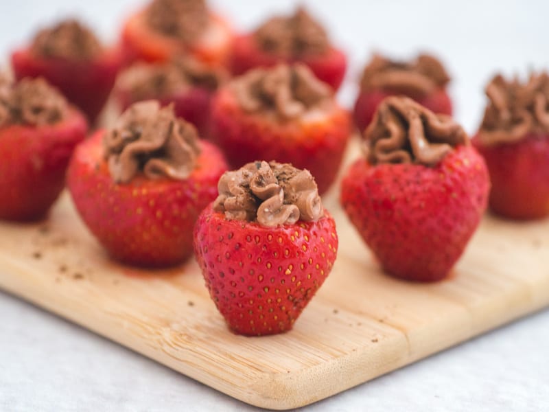 Chocolate cheesecake stuffed strawberries sprinkled with chocolate shavings and arranged on a cutting board.