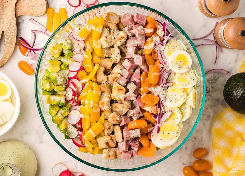 Overhead view of a cobb salad is a large glass bowl. 