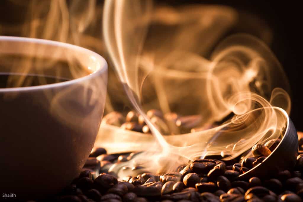 cup of coffee with steam and coffee beans.