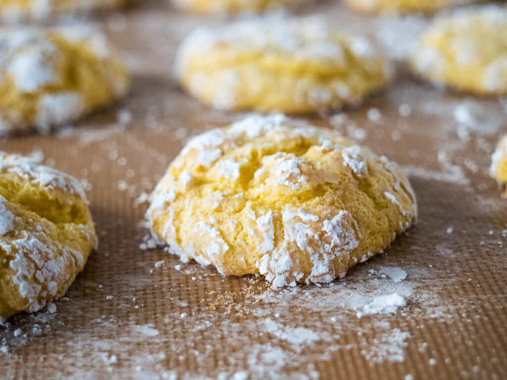 Cool whip cookies on parchment with powdered sugar.