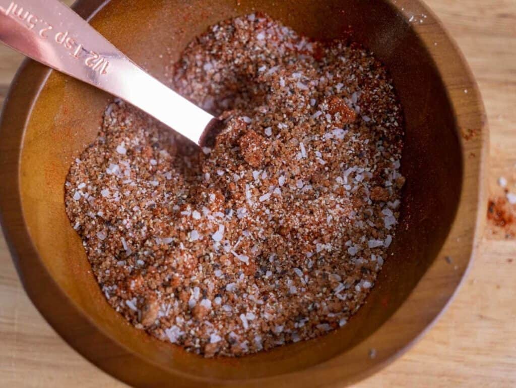 Mixing the pork rub spices in a wooden bowl with a copper teaspoon.