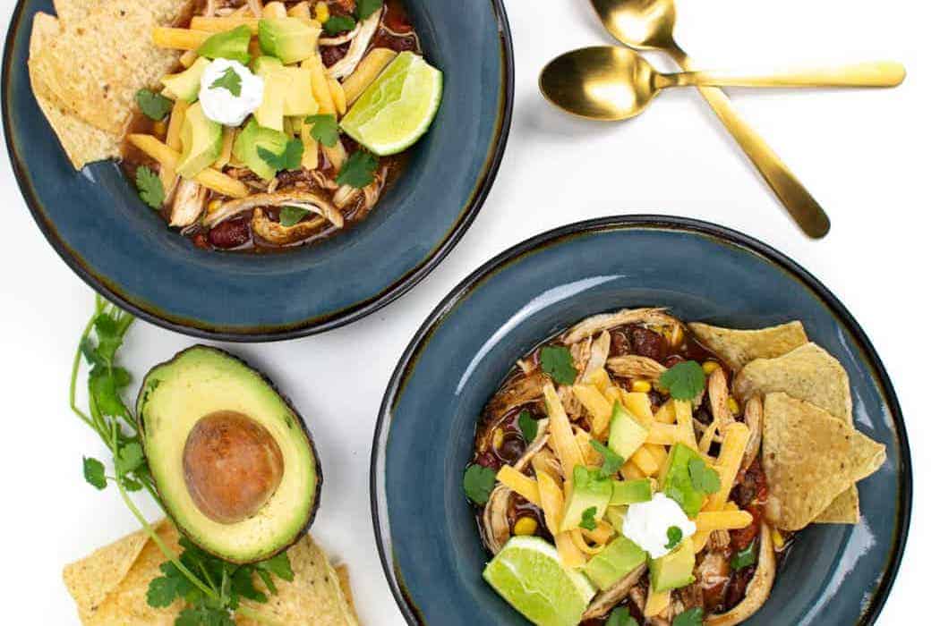 Chicken tortilla soup in two blue bowls.