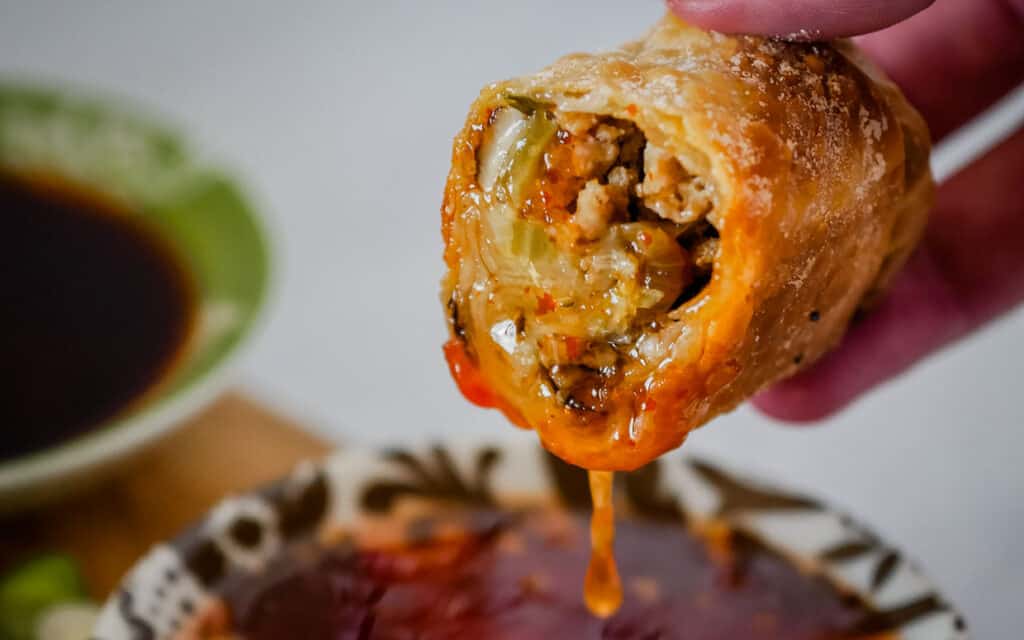 Egg roll cut in half and dipped into sweet chili sauce.