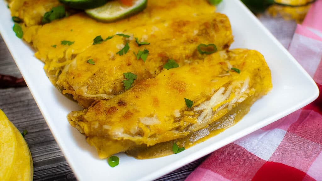 plate of air fryer enchiladas topped with lots of cheese.