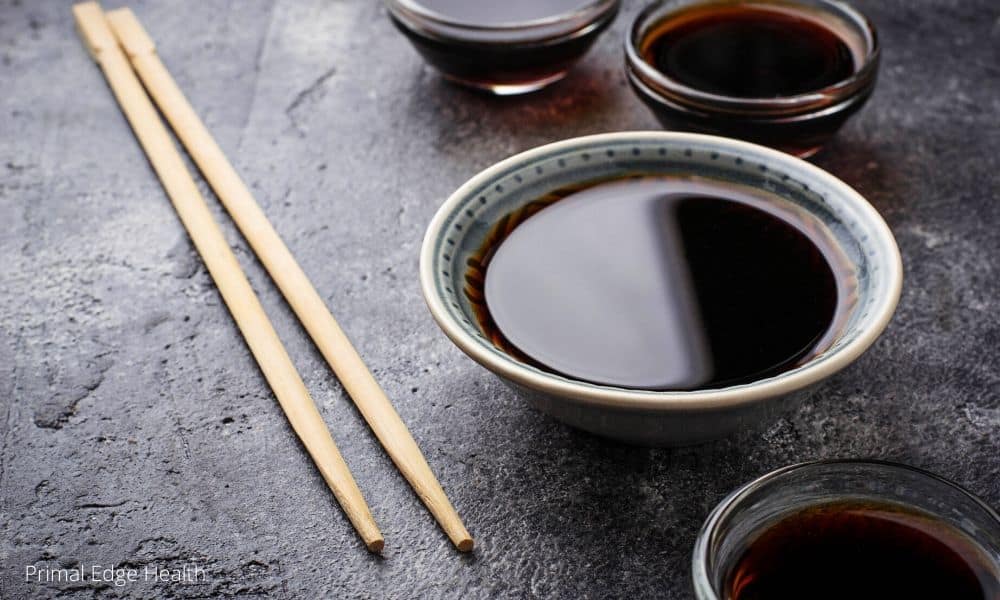 small bowls of soy sauce with wooden chopsticks on dark background