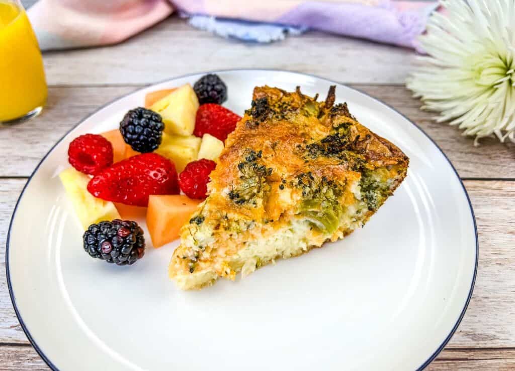 Broccoli 3-Cheeese Quiche on a plate with fruit.