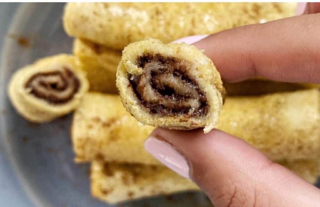 Holding a sliced French toast roll with cinnamon.