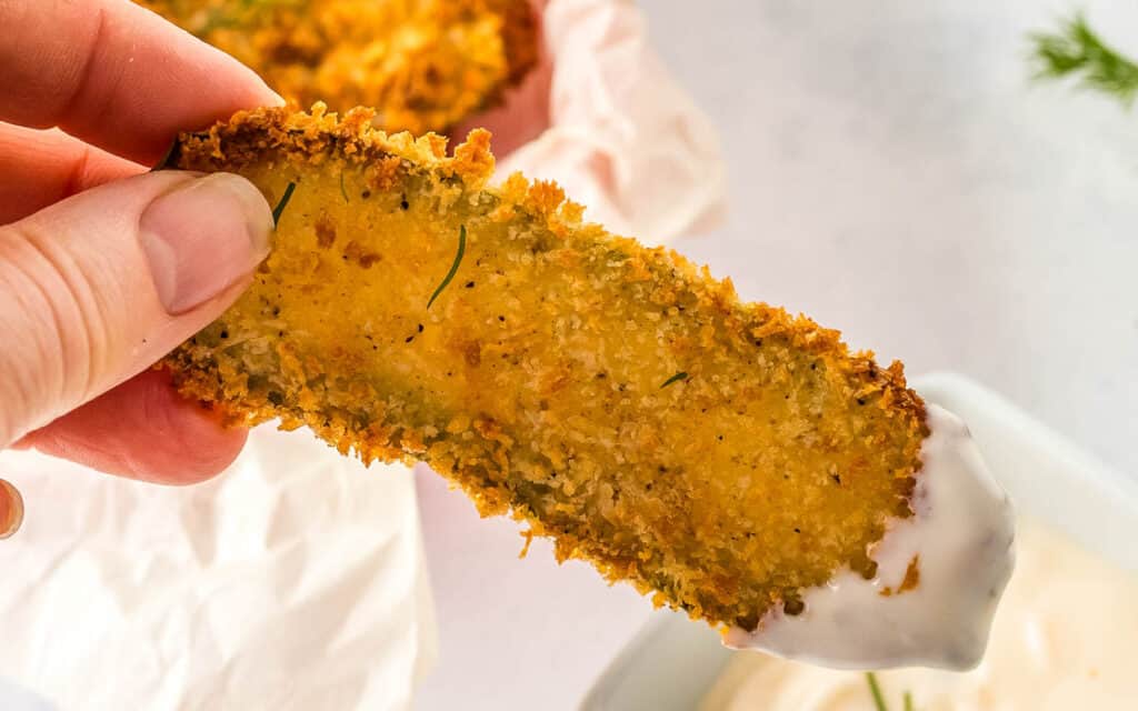 Dipping a fried pickle into ranch dressing.