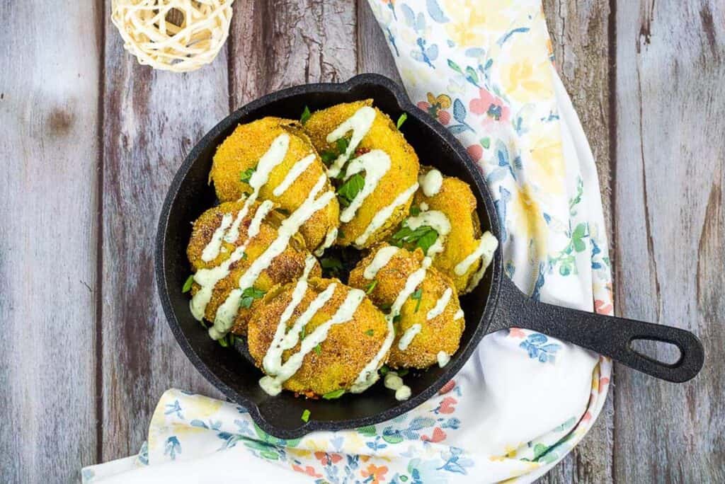 Fried Tomatillos in a black cast iron pan.