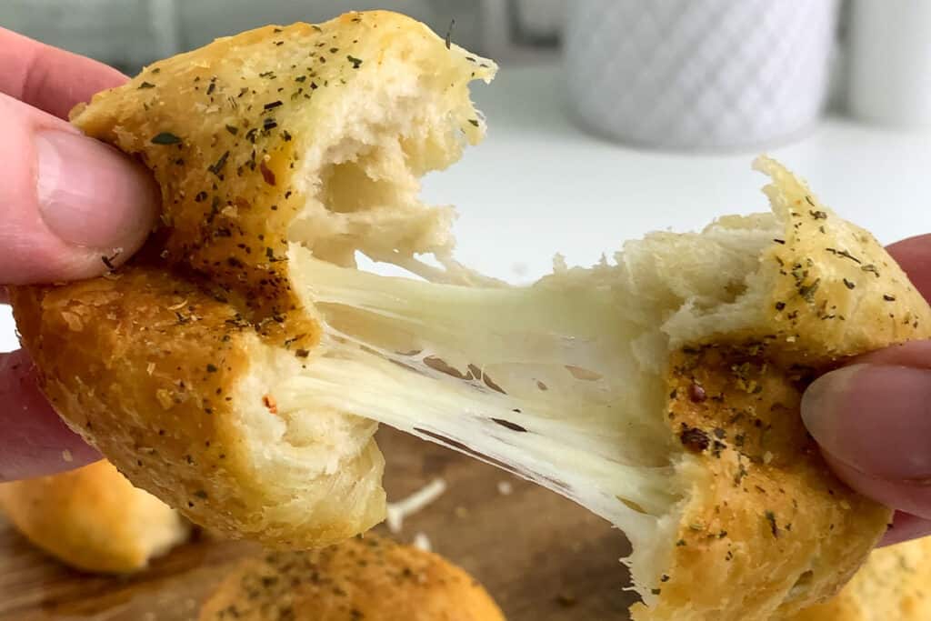 pulling apart a biscuit stuffed with mozzarella cheese.