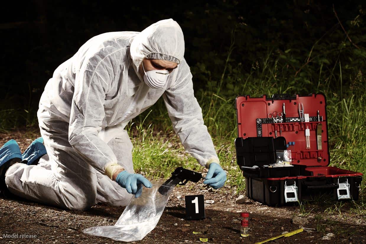 A person in coveralls collecting evidence of a crime.