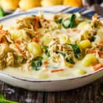 Bowl of copycat Olive Garden chicken gnocchi soup in a bowl with breadsticks in the background.