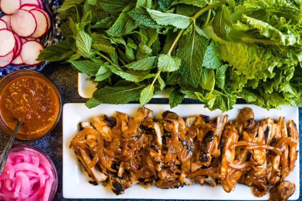 overhead shot of gochujang chicken with herbs and lettuce.