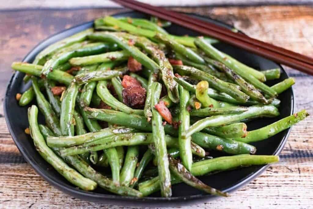 Low angle shot of a plate of dry fried green beans.