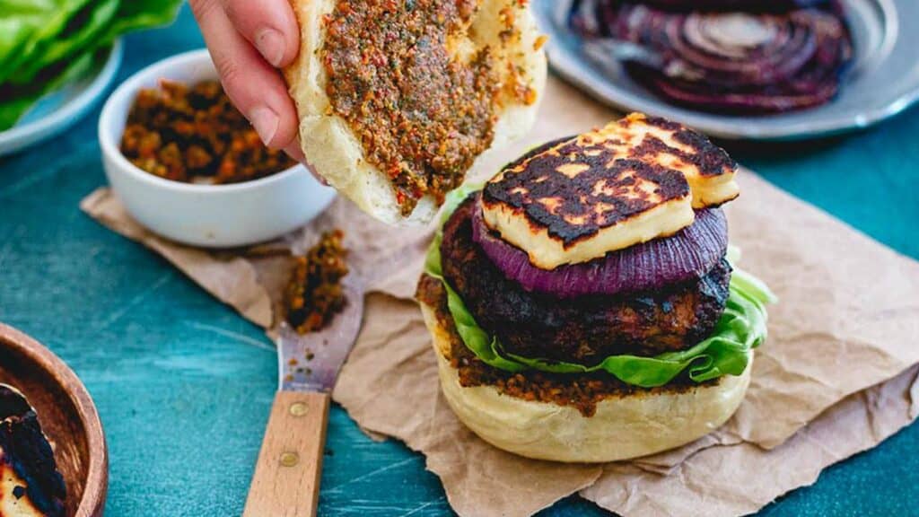 Grilled halloumi lamb burger on a bun with pesto spread.