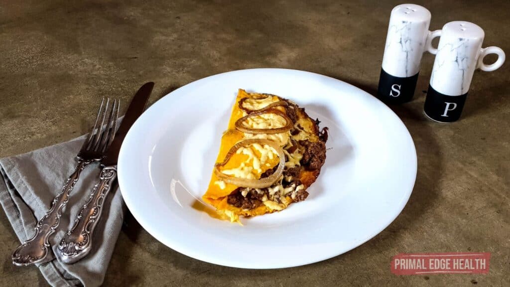 cheeseburger omelette with ground beef on plate next to salt and pepper shakers