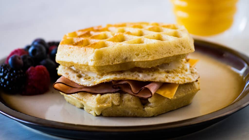 Breakfast sandwich with ham, egg and cheese on waffles.