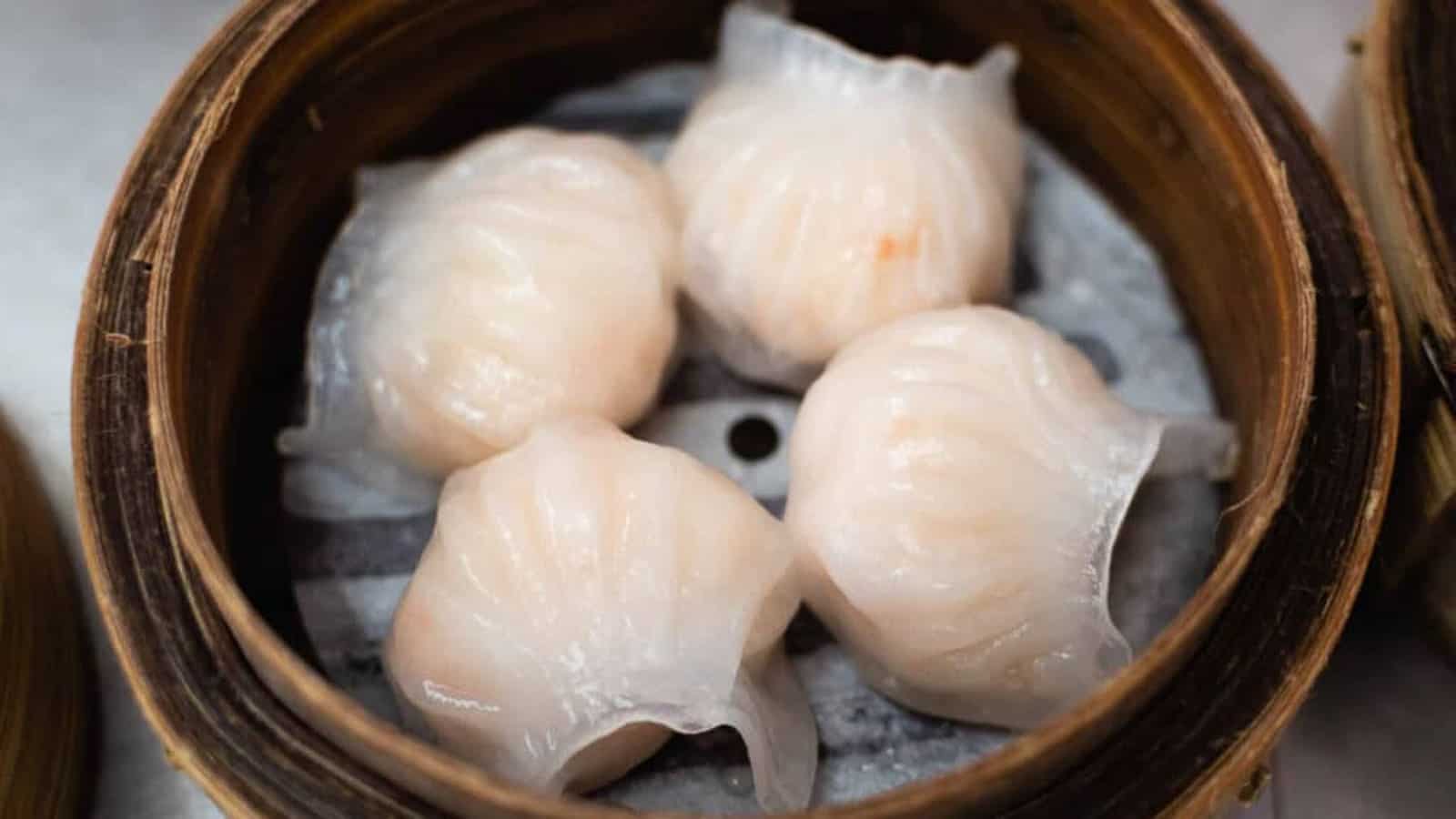 4 har gow shrimp dumplings in a bamboo steamer basket.