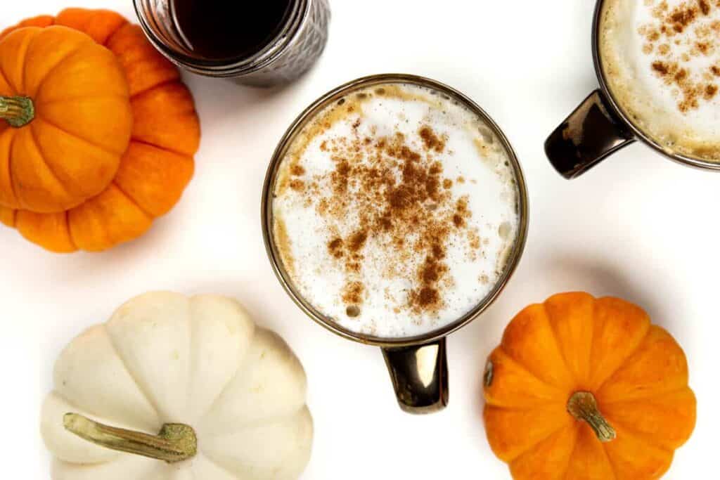 closeup of a pumpkin spice latte with pumpkin spice syrup and mini pumpkins