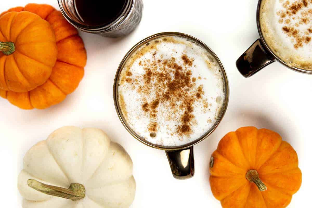 Closeup of a pumpkin spice latte with pumpkin spice syrup and mini pumpkins.