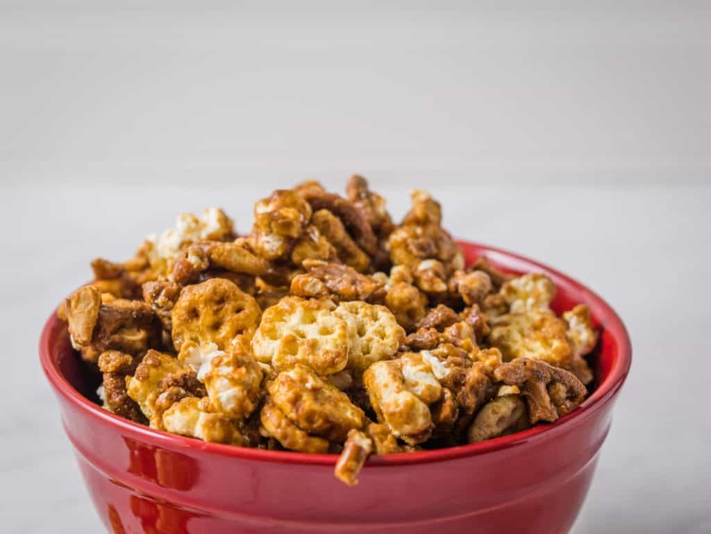 Red bowl full of honeycomb snack mix covered in caramel sauce.