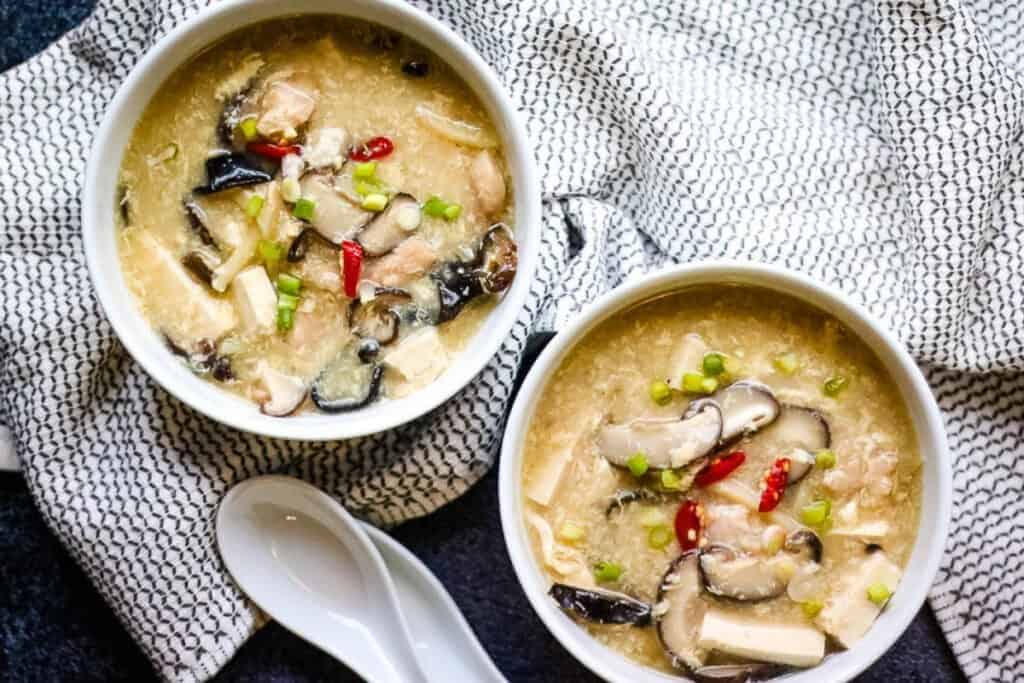 Overhead shot of two white bowls with chicken hot and sour soup.