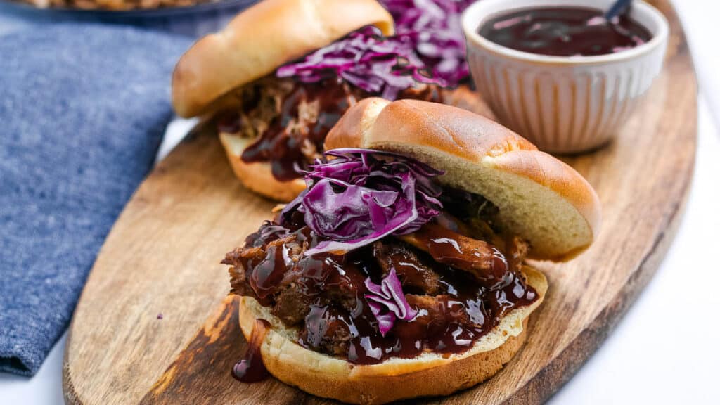 pulled pork on a bun with sauce and cabbage.