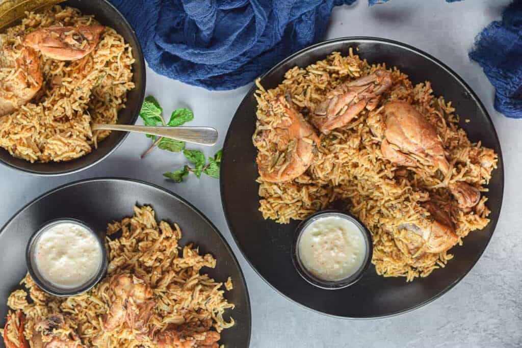 Overhead shot of 3 plates of chicken biryani.