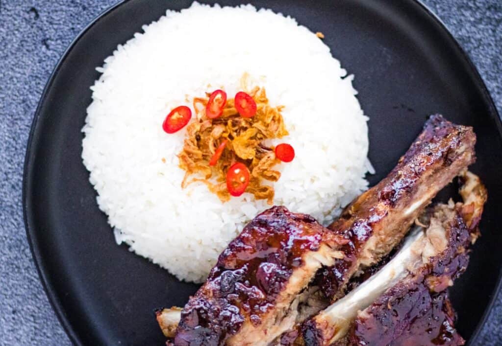 Coconut rice garnished with fried shallots with spare ribs on the side.