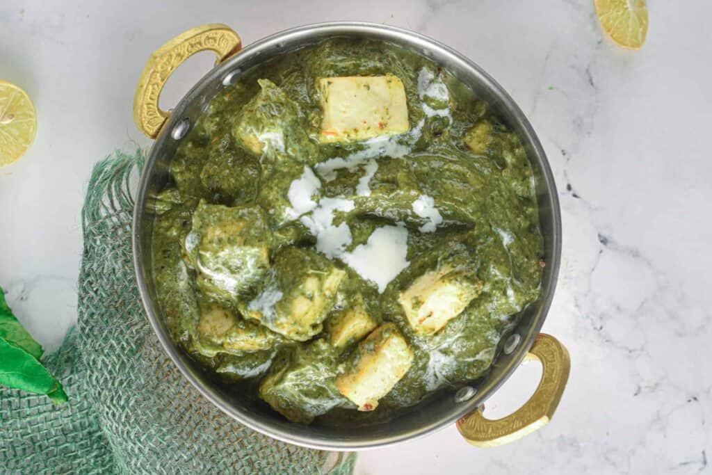 Overhead shot of palak paneer in a metal serving dish.