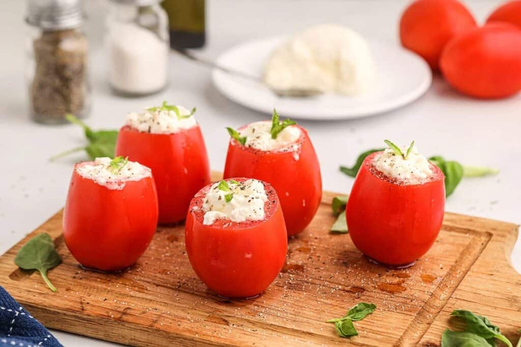 Tomatos filled with burrata on a serving tray.