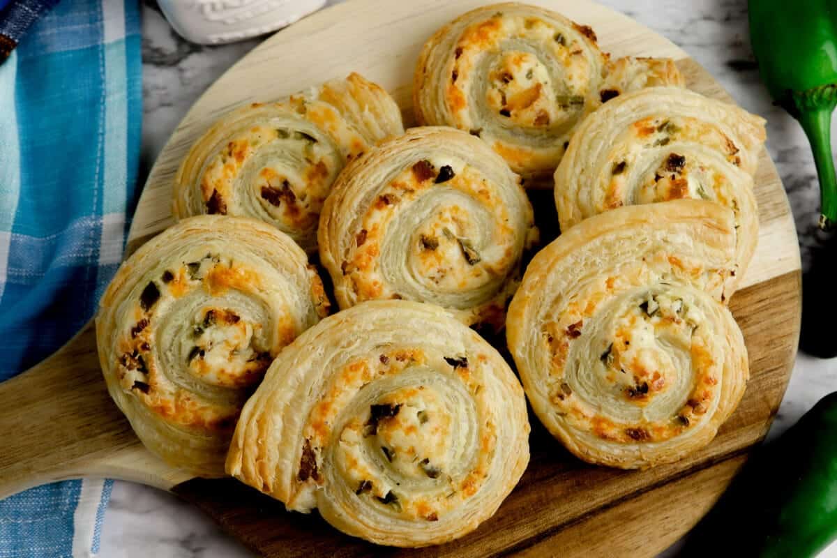 Puff pastry pinwheels on a round wooden cutting board.