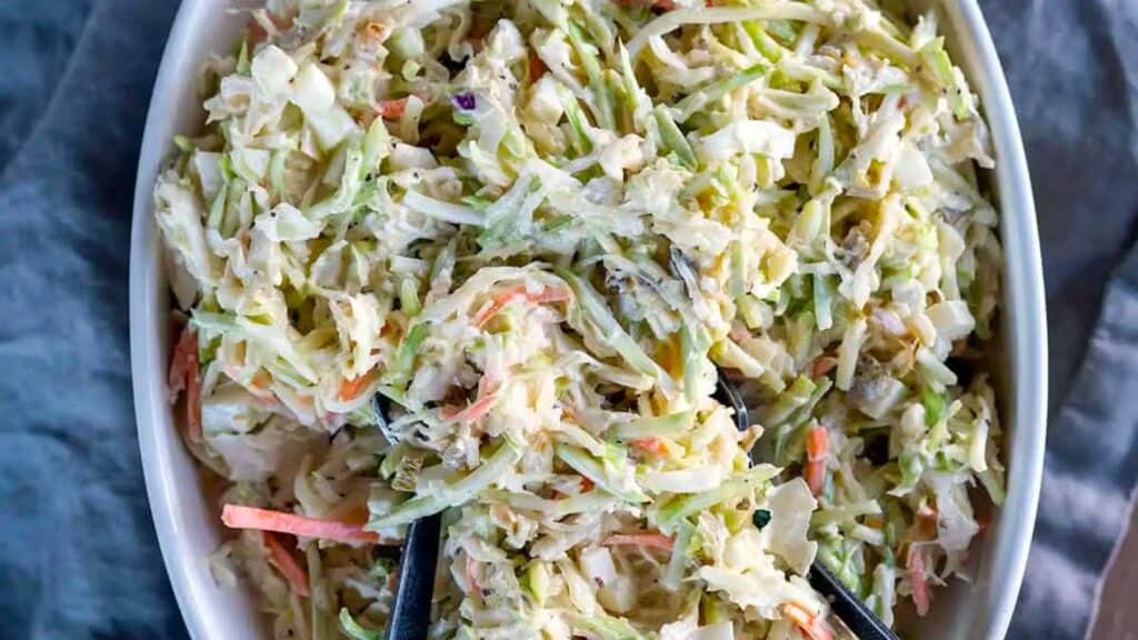 Candied Jalapeno Coleslaw in bowl with serving utensils.