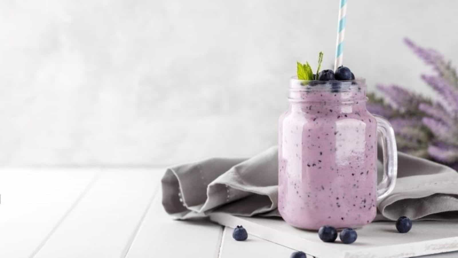 Blueberry avocado smoothie in a mason jar with blueberries on top.