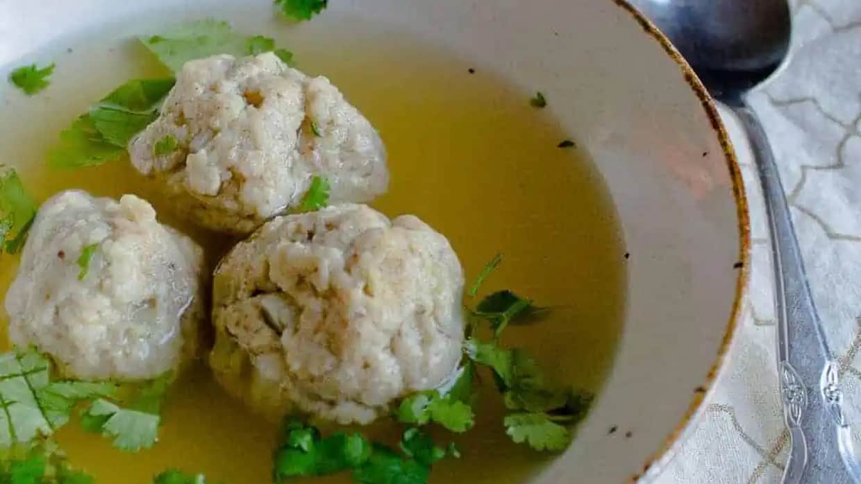 Close up on 3 matzo balls in soup.
