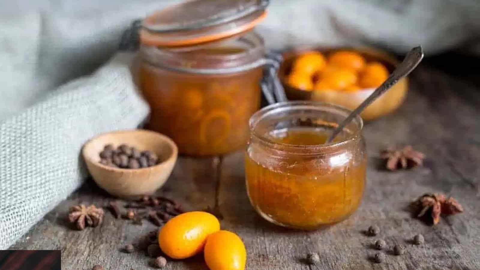 Kumquat jam jar with kumquats and spices in background.