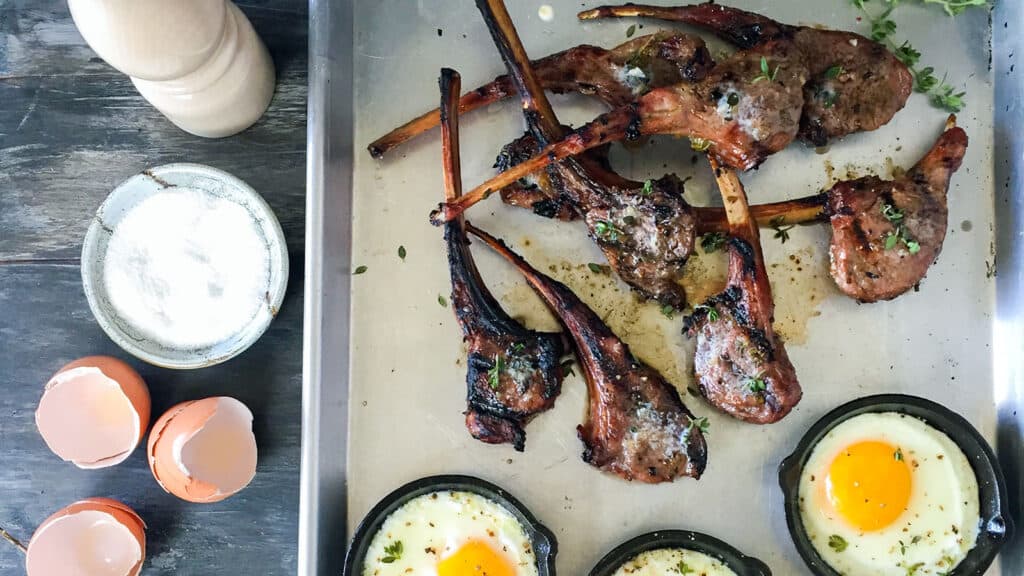 grilled lamb chops on tray with fried eggs.