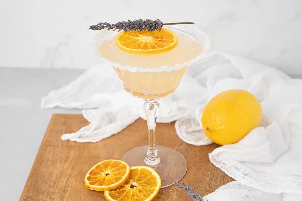 A martini with a lemon ring and lavender garnish.