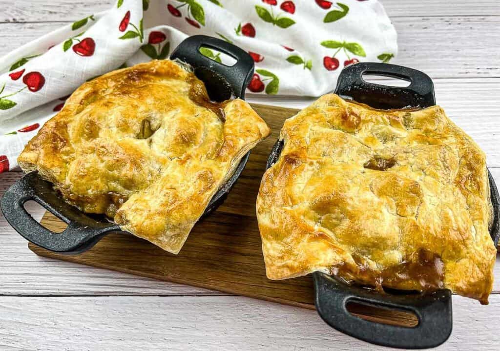 Two Leftover Roast Beef Pot Pies on a counter with a cloth nearby.