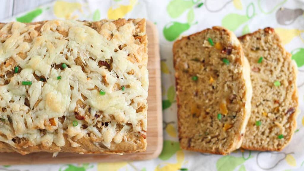 Loaded cheddar bacon bread sliced on a cutting board.