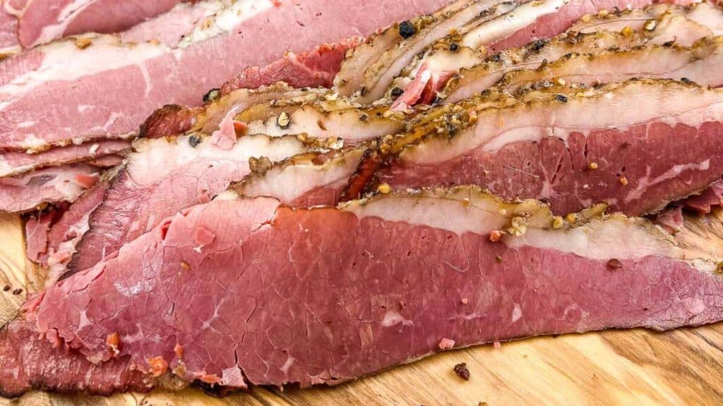 Close view of sliced Montreal smoked meat on a cutting board.