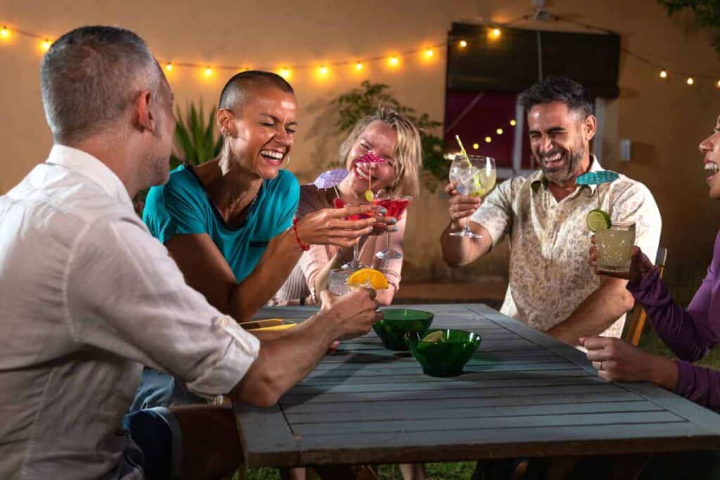 A group of friends with cocktails at a table at night.